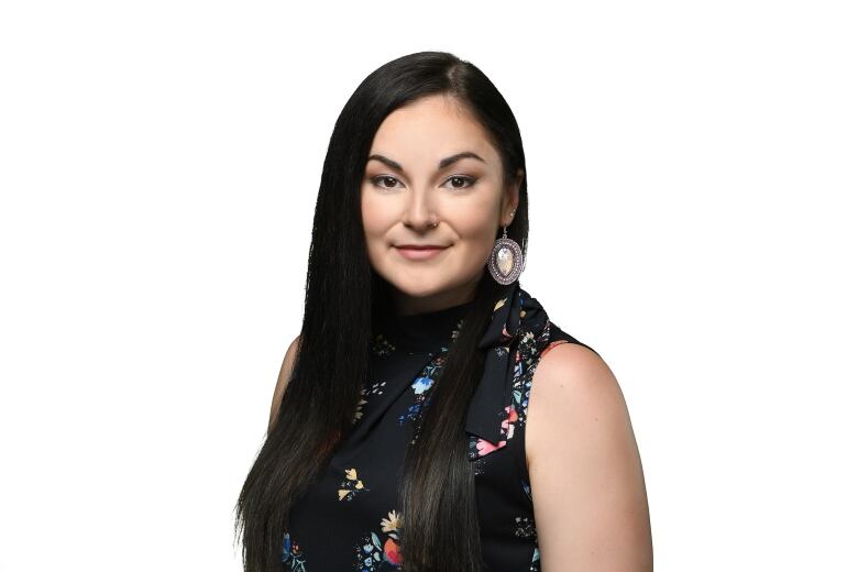 a woman with long hair wearing a floral shirt poses for a head shot. 