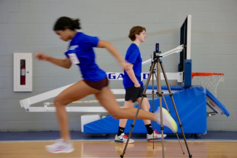 A young woman runs past another participant in a sprinting test.