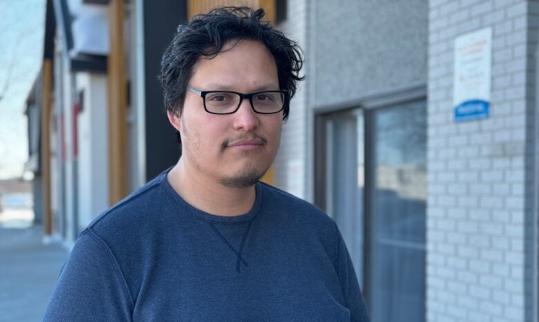 Man in a blue shirt standing outside.