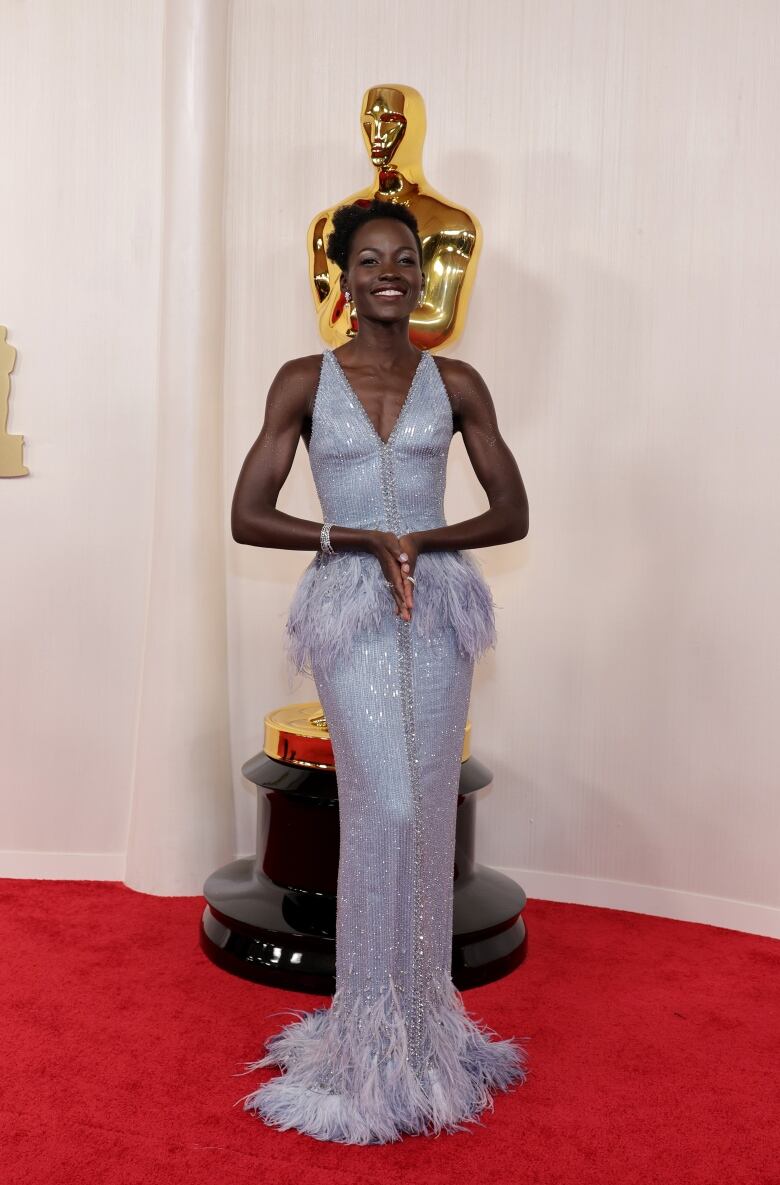 A woman poses in a blue dress on a red carpet.