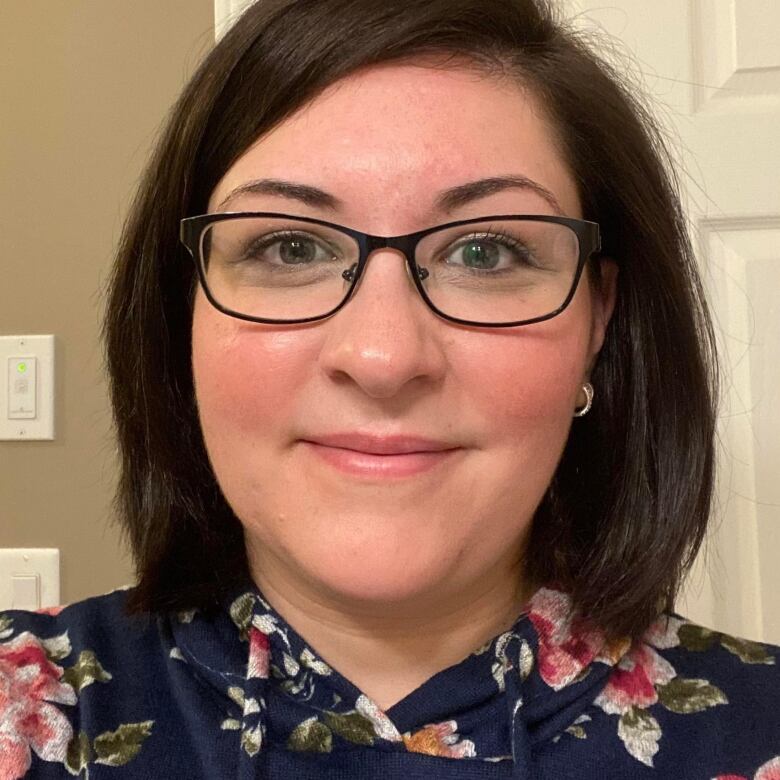 A close up image of a woman with brown hair wearing glasses.