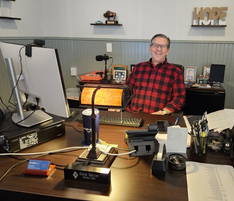 A man in a plaid shirt in an office.