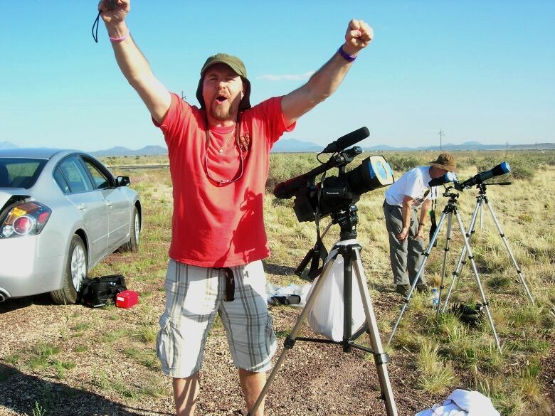 A man stands with his arms outstretched and appears to be shouting with joy.