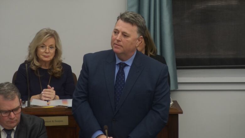 Premier Dennis King stands in the legislature wearing a blue suit.