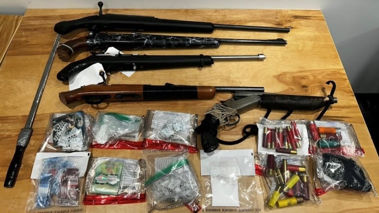 Illegal guns, cocaine, meth, ammo and cash on a table after RCMP seized it. 