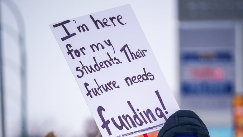 A person holds a sign that says 