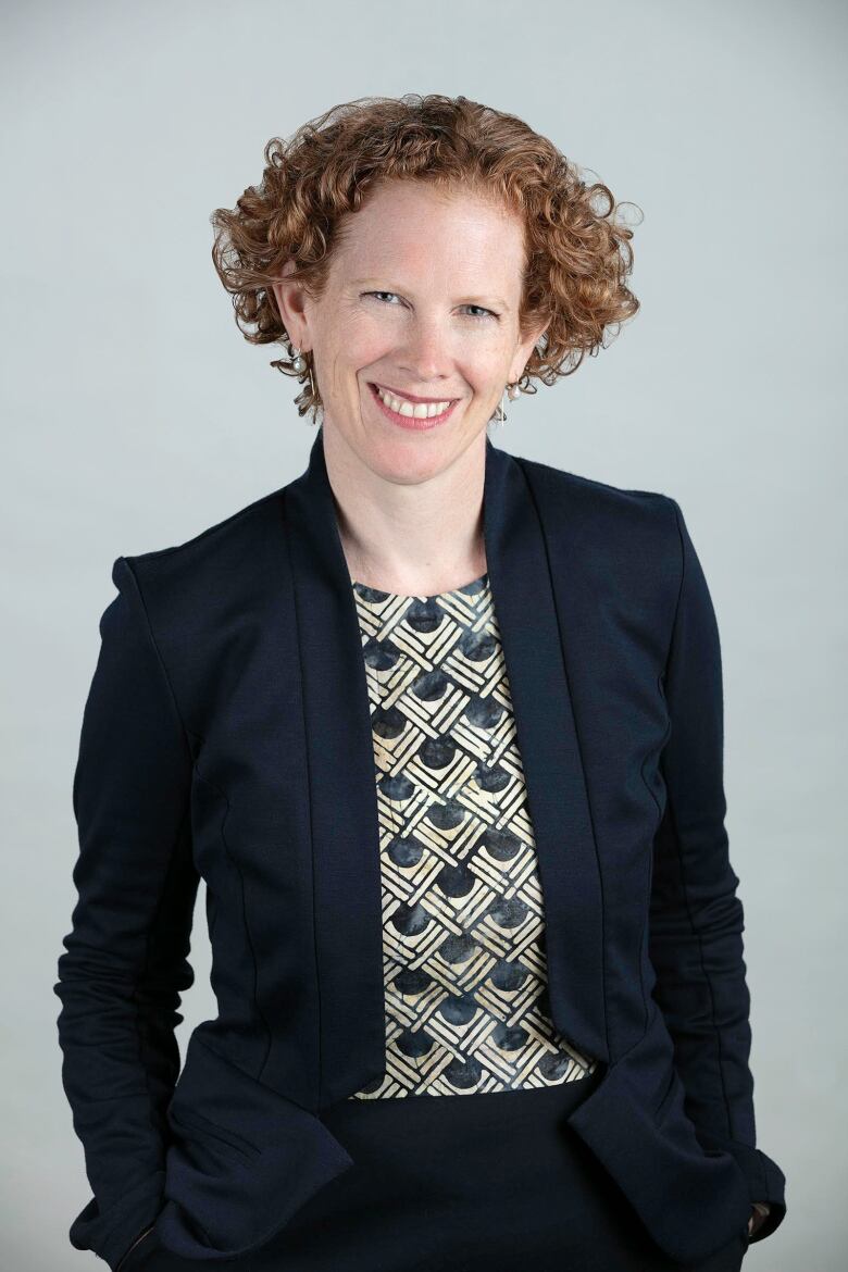 A woman with short red hair in a black suit. 