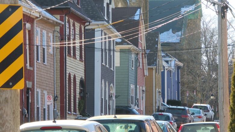 The view of a Charlottetown street with multi-coloured houses and parked cars. 