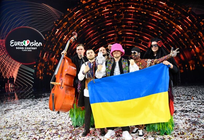 A group of musicians pose on the Eurovision stage with a Ukraine flag. 