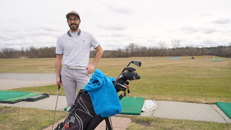 A golfer poses in front of a driving range tee box