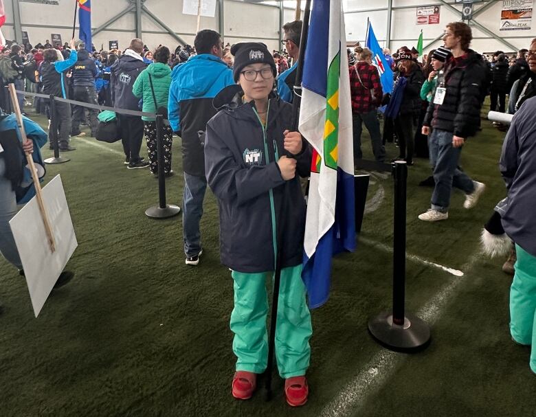 Young teenager stands with AWG flag