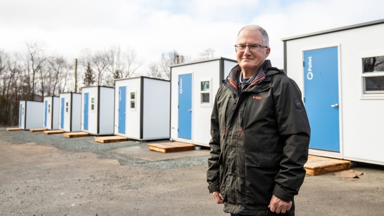 A man stands in front of newly constructed tiny shelters