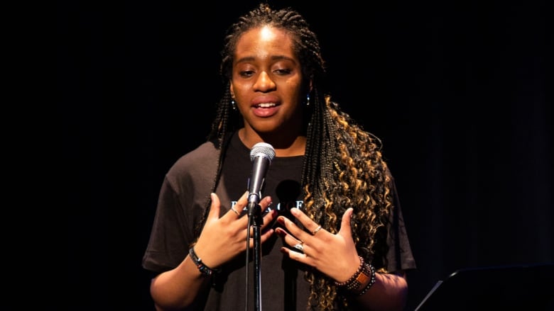 A woman has a passionate expression on her face as she speaks into a mic.