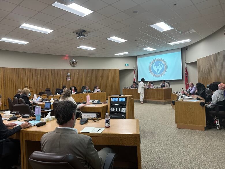 A board room with people sitting in semi circles. 