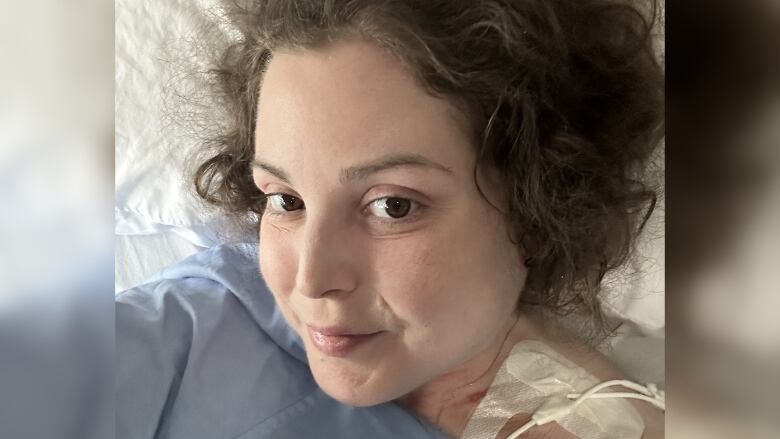 A woman is pictured taking a selfie in a hospital bed.