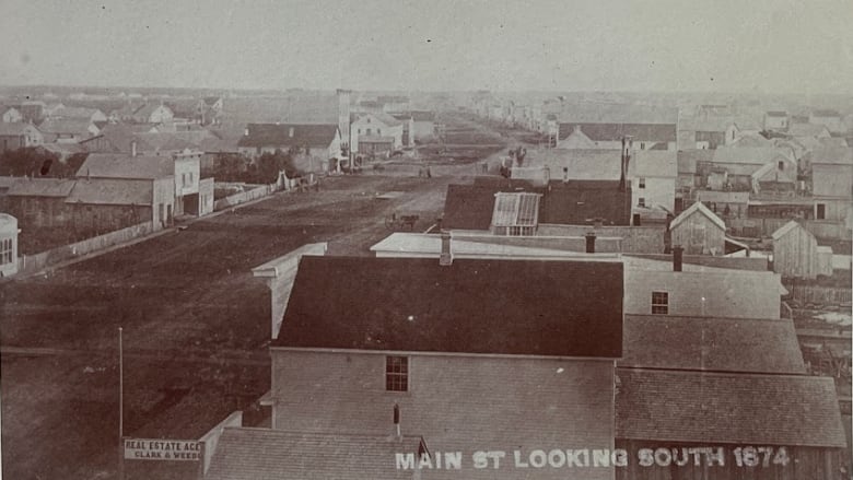 Black and white photo of wooden buildings lining a dirt road