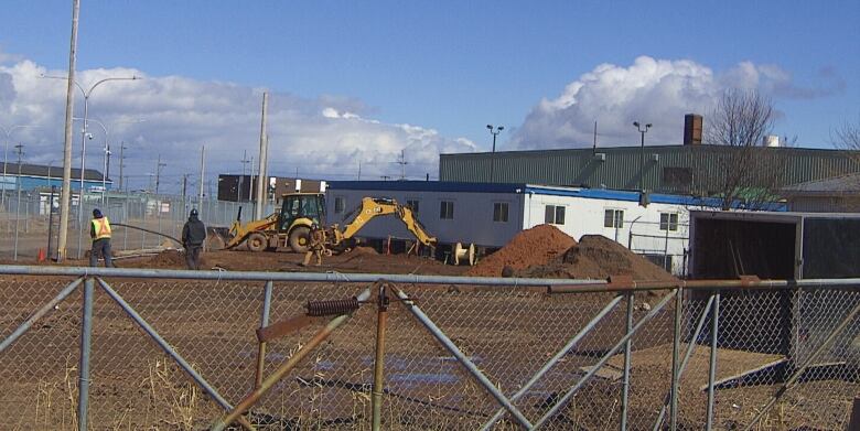 Construction around small white building.