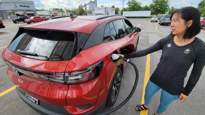 A woman charges her electric car at a charging station.