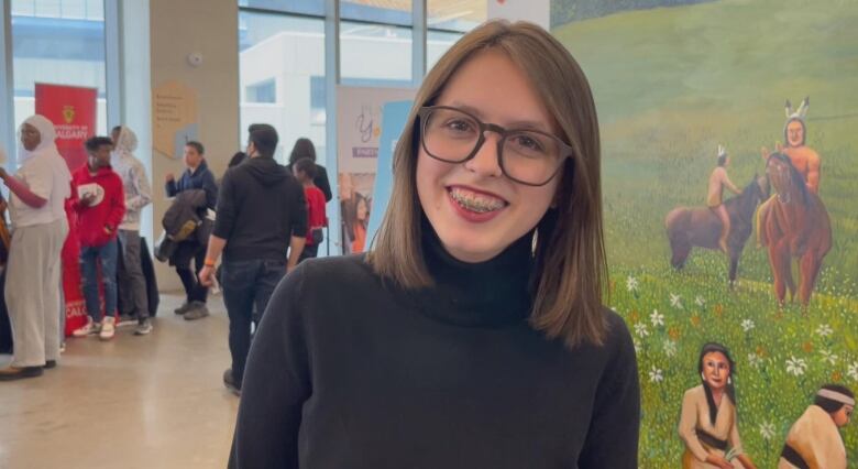 a young woman with glasses smiles.