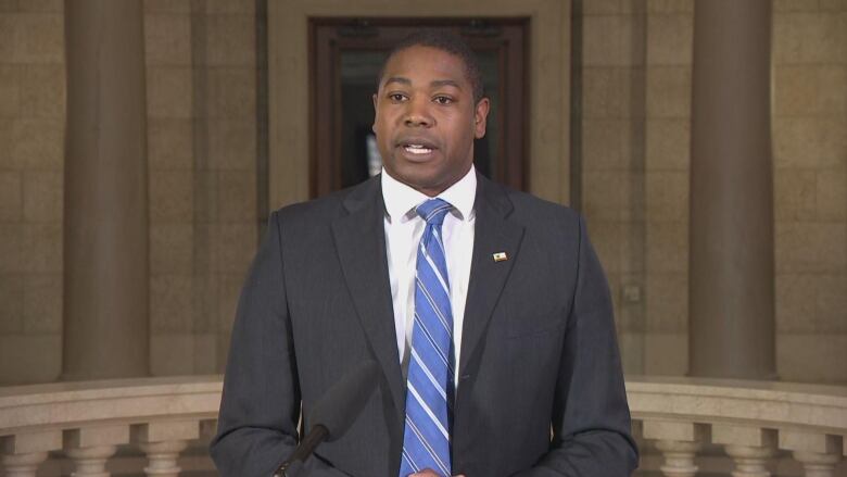 A man in a suit stands at a podium 