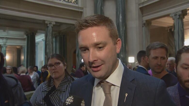 A man in a suit with a beige tie