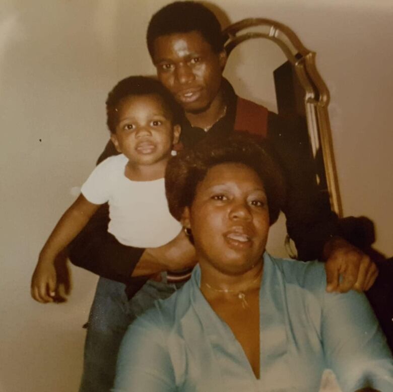 Picture of a baby in the arms of a man and a woman posing in front.