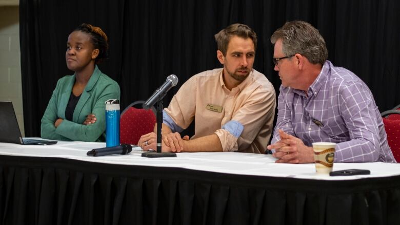 Three professionals sit at a table.