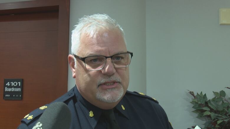 A high-ranking police officer speaks outside a boardroom.