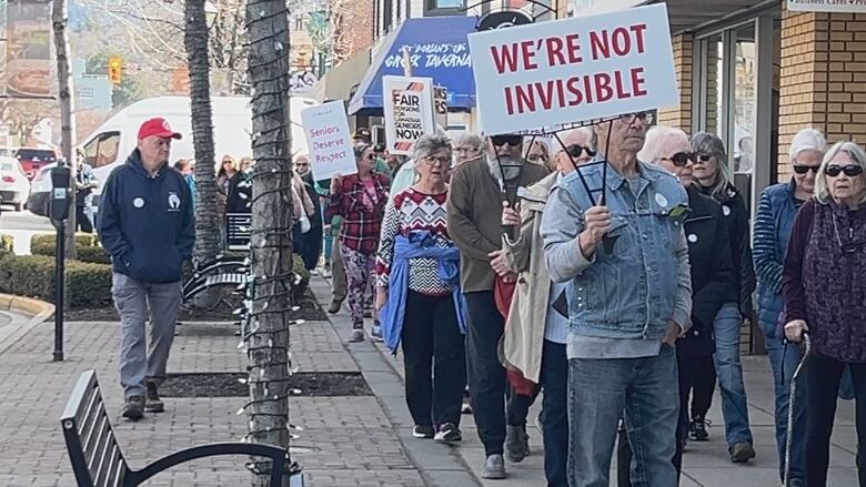 People in Vernon, B.C., hold placards to protest stagnating pensions.