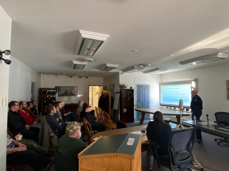 A group of people watching a slideshow presentation.