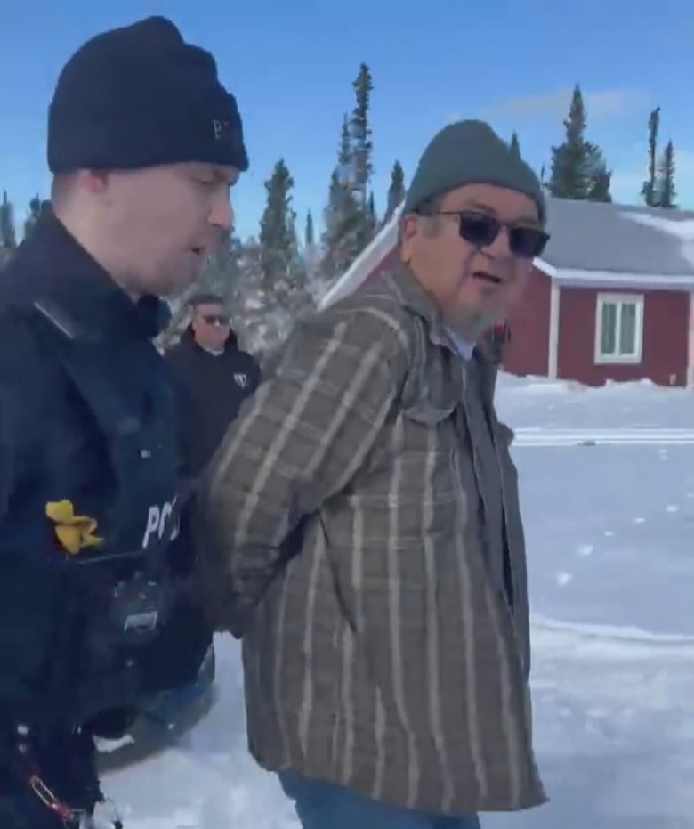 A man is led away by police officer.