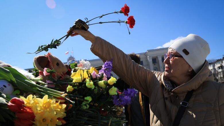 A woman places flowers at a makeshift memorial. 