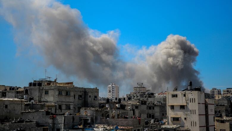 Smoke billows in a city following bombardment.