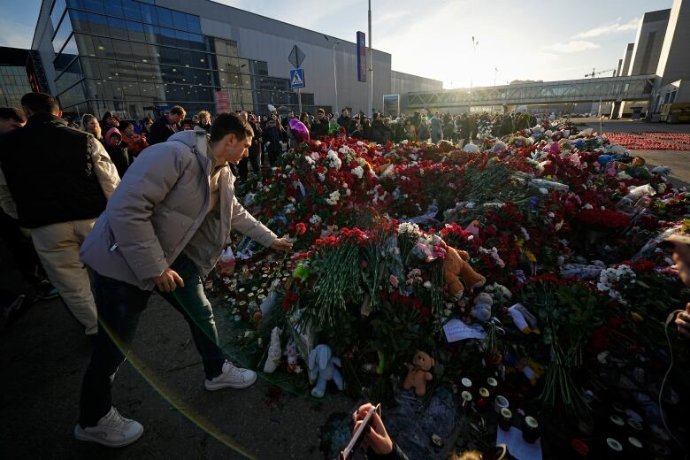 People place flowers at a makeshift memorial in front of the Crocus City Hall.