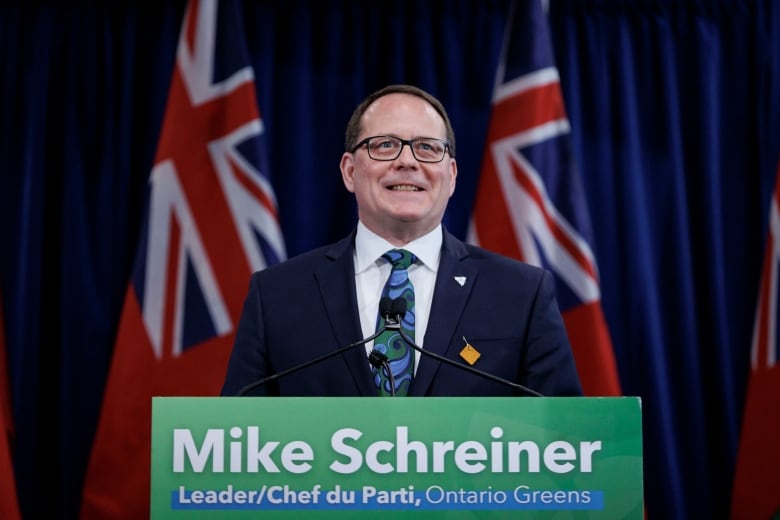 A man in a suit stands behind a podium