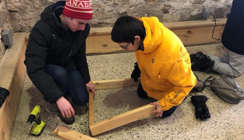 Two boys holding wood before drilling screws into it.