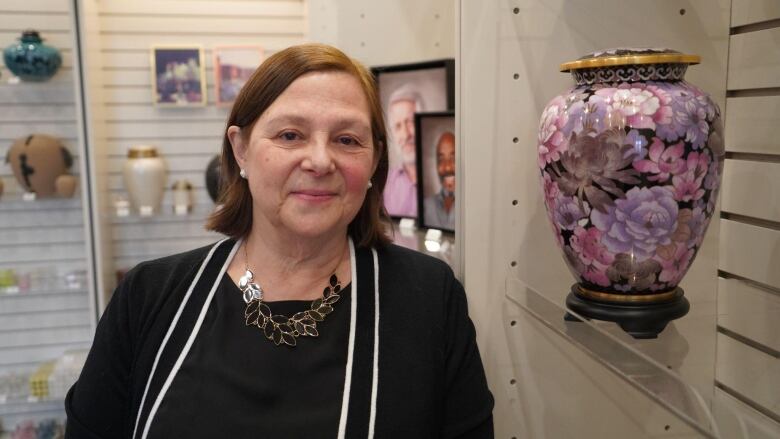 A woman stands next to an ornamental cremation urn.