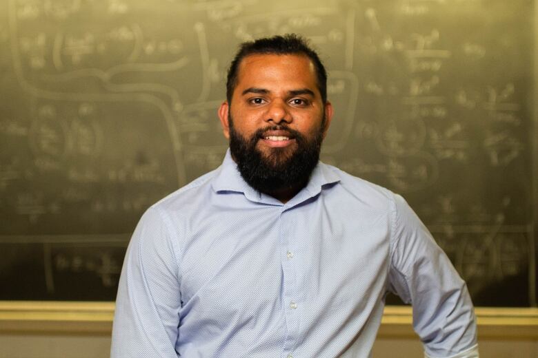 A scientist poses in a classroom.