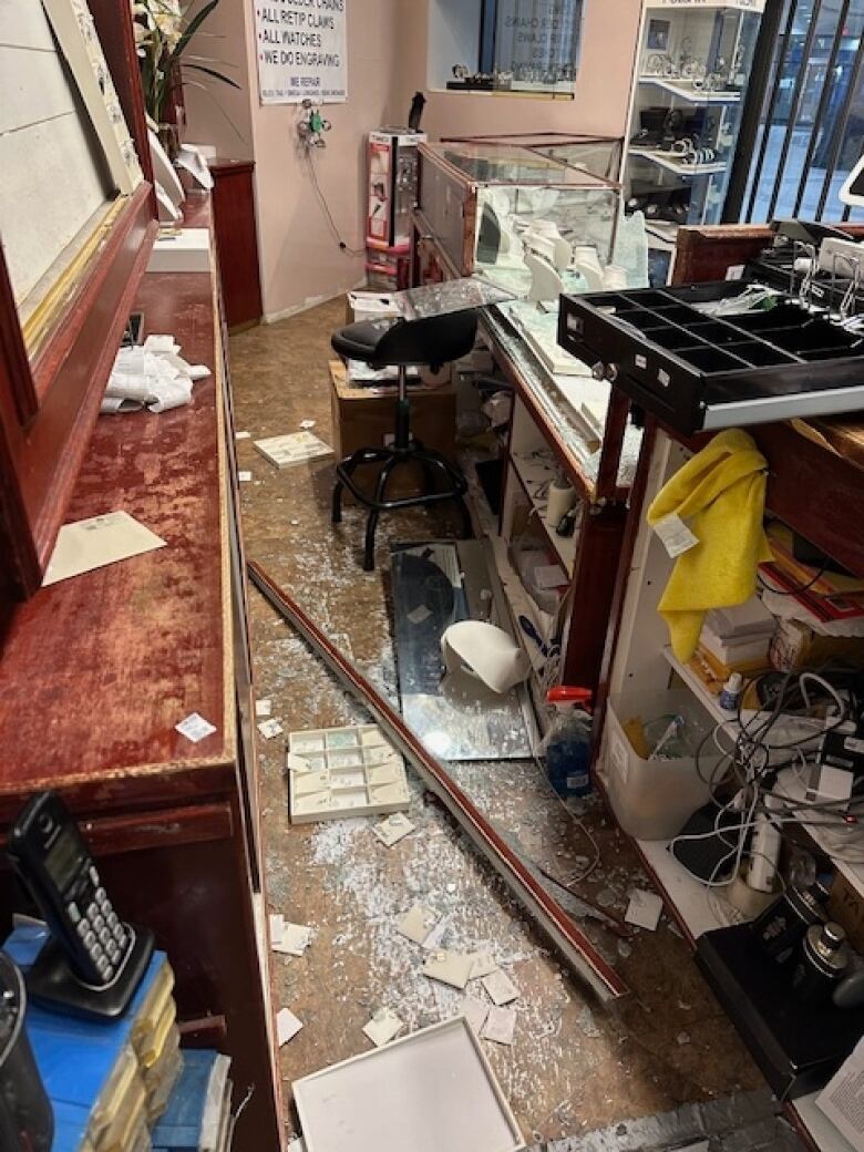 Shattered glass and overturned display cases are shown at a robbed jewelry store.