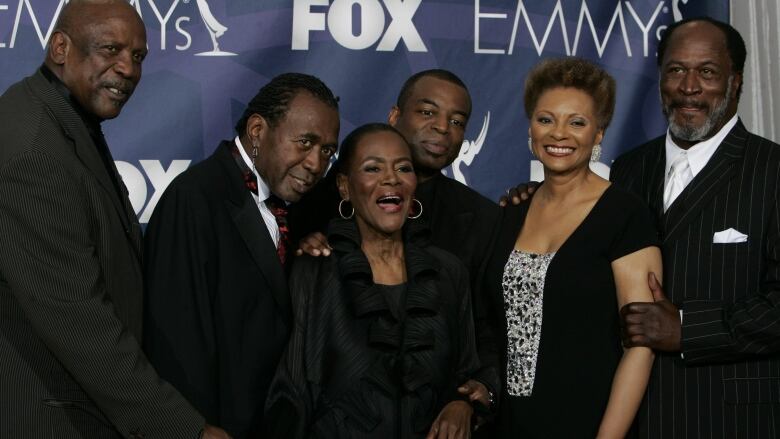 Six African Americans, men and women wearing suits and dresses, pose for a photograph at an event.