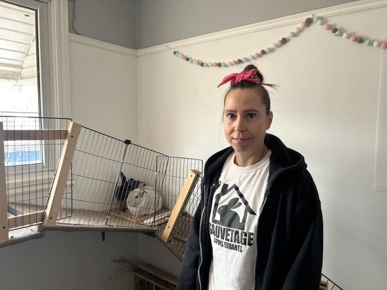 A woman stands in front of a rabbit.