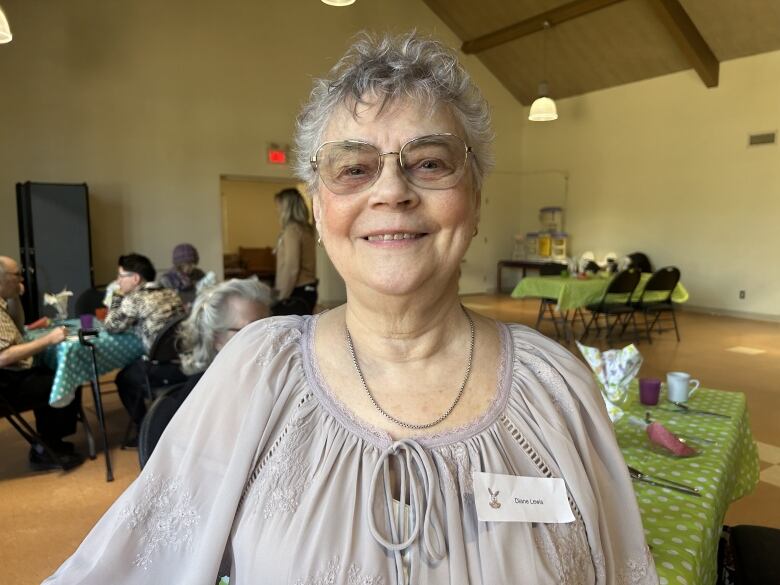 An elderly woman smiling with a name tag. 