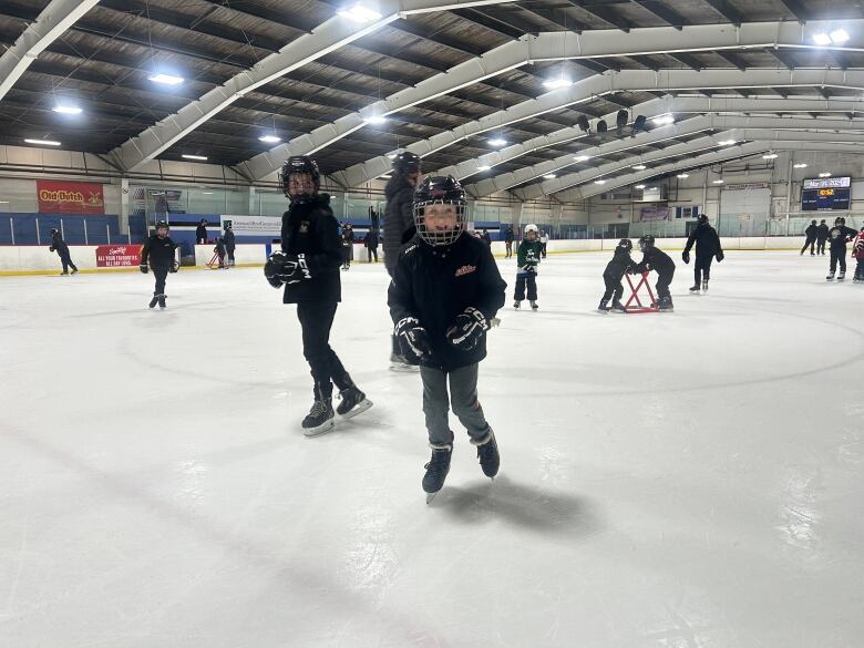 A group of people of all ages skate around an ice rink