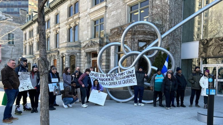 People standing outside the office of Quebec's Premier with banners.