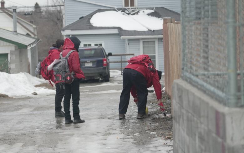 Employees with a local outreach group pick up discarded needles in downtown Timmins.