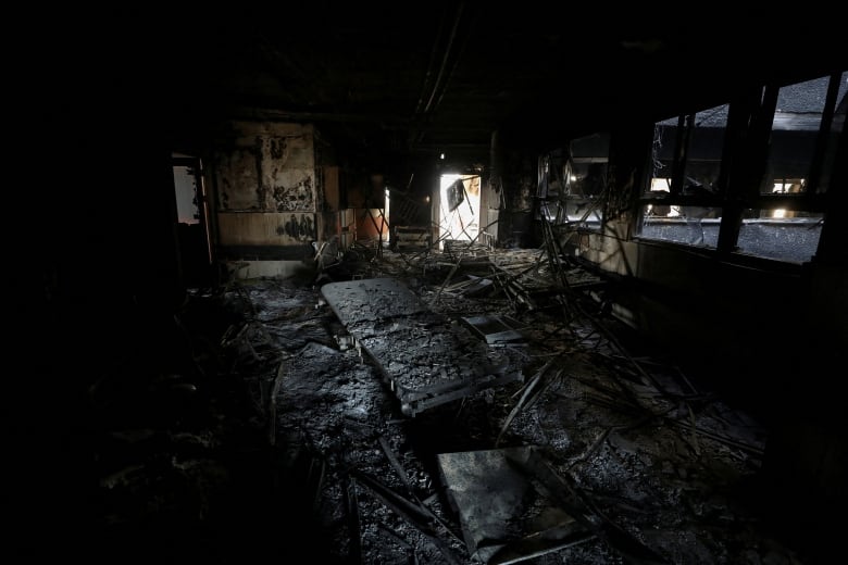 Burnt beds lies on the floor inside a burnt room.