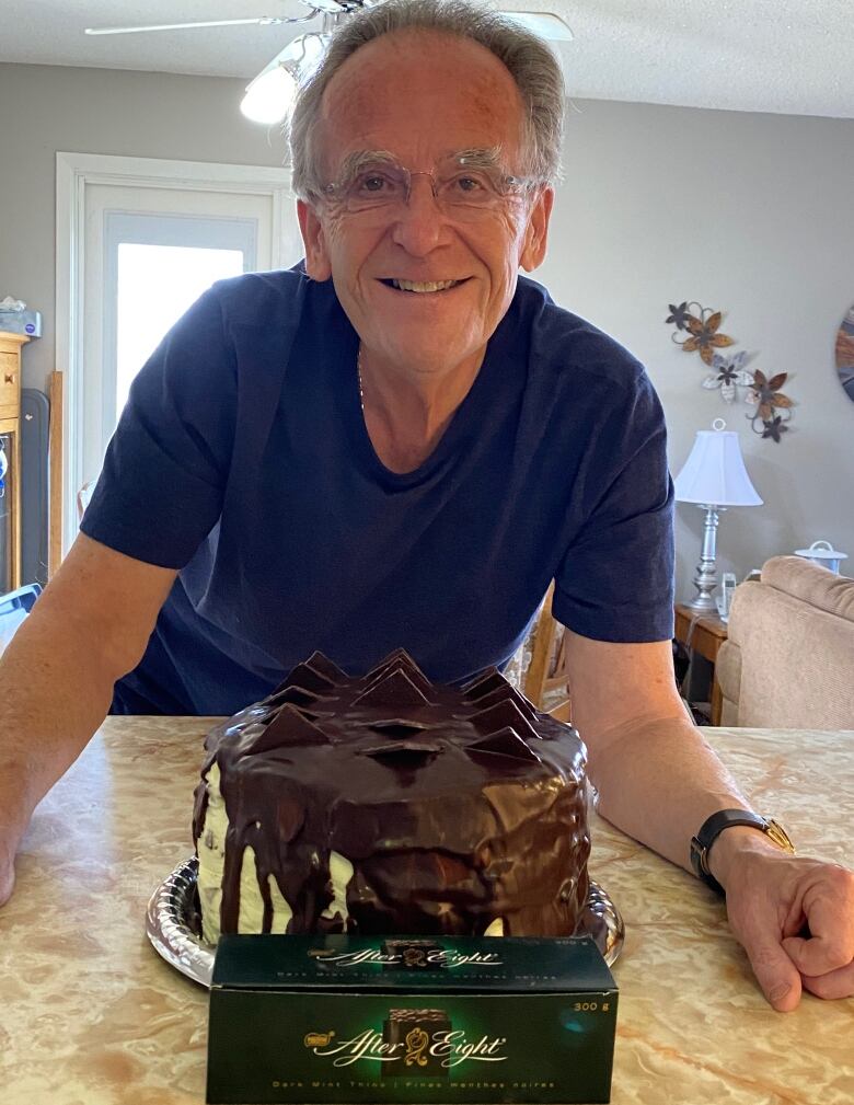 A man smiling in front of a cake.