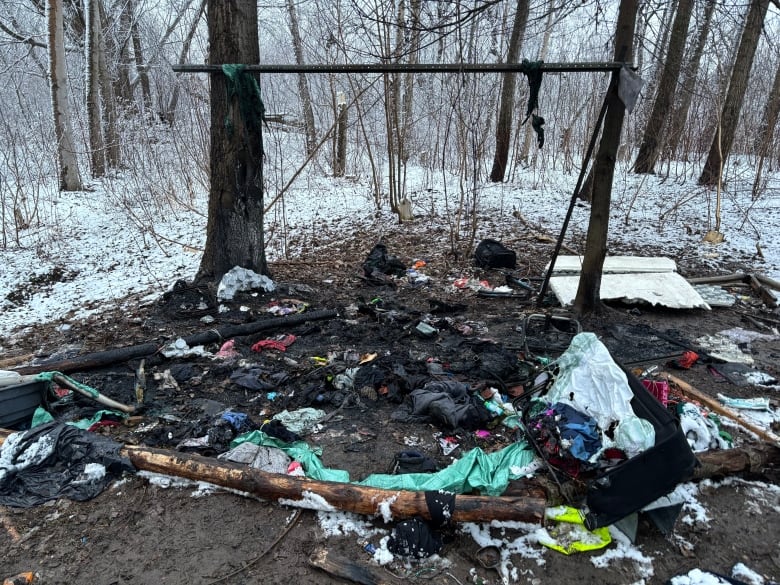 A photo shows a burned out tent on the snowy ground in a wooded area.