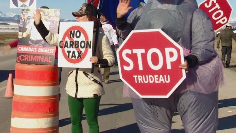 Protesters hold signs that say 