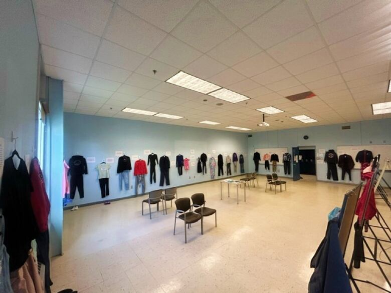 A classroom is seen with outfits hung along each of the walls. Each outfitted is accompanied by a piece of paper describing the clothing.